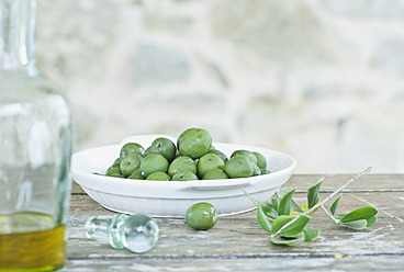 Italy, Tuscany, Magliano, Green olives in plate and jar of olive oil - WESTF017336