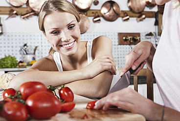 Italien, Toskana, Magliano, Zwei junge Frauen schneiden Tomaten in der Küche, lächelnd - WESTF017400