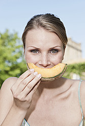 Italy, Tuscany, Magliano, Close up young woman eating honey melon, portrait - WESTF017435