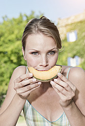 Italy, Tuscany, Magliano, Close up young woman eating honey melon, portrait - WESTF017437