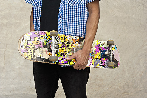 Germany, Düsseldorf, Close up of skateboarder holding his deck in public skatepark - KJF000152