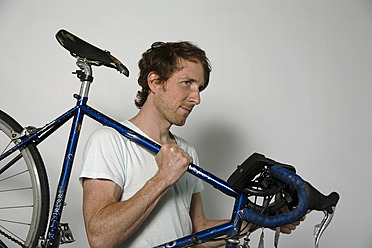 Man carrying racing cycle against white background - DBF000148