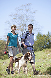 Deutschland, Oberbayern, Paar beim Wandern mit Hund, lächelnd - MAEF003850