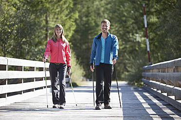 Deutschland, Oberbayern, Pärchen beim Nordic Walking auf Brücke - MAEF003865