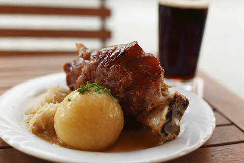 Deutschland, Bayern, Bamberg, Schweinshaxe mit Kartoffelknödel im Teller, Nahaufnahme, lizenzfreies Stockfoto