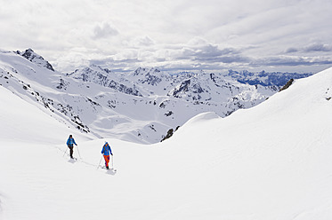 Austria, Stuben, Young couple doing telemark skiing on arlberg mountain - MIRF000300