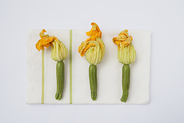 Zucchini with flowers on tea towel, close up - GWF001576