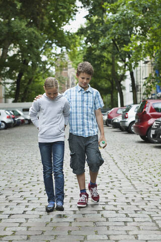 Deutschland, Berlin, Junge und Mädchen gehen als Paar auf der Straße, lizenzfreies Stockfoto