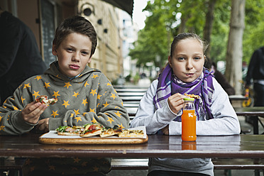 Germany, Berlin, Boy and girl eating pizza at cafe - WESTF017507