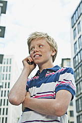 Germany, Berlin, Teenage boy using cell phone in city - WESTF017515