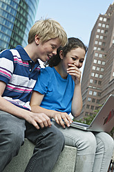 Deutschland, Berlin, Jugendliches Paar benutzt Laptop in der Stadt - WESTF017546