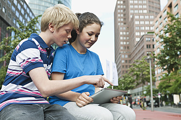 Germany, Berlin, Teenage couple using digital tablet in city - WESTF017549