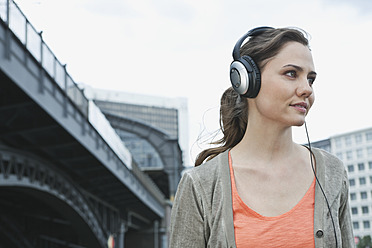 Germany, Berlin, Woman with headphones listening to music - WESTF017552