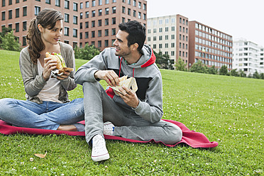 Germany, Berlin, Couple eating food in park - WESTF017605