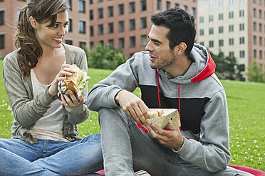 Germany, Berlin, Couple eating food in park - WESTF017606