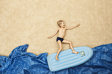 Deutschland, Junge auf aufblasbarem Floß im Wasser am Strand - BAEF000280