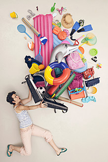 Germany, Artificial scene with woman opening baggage full of beach toys - BAEF000320