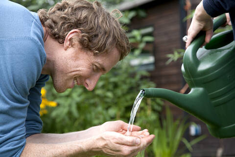 Mann hält Wasser aus einer Gießkanne, lizenzfreies Stockfoto