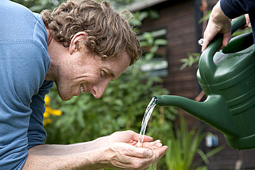 Mann hält Wasser aus einer Gießkanne - DBF000170
