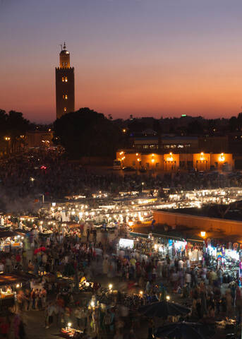 Marokko, Marrakesch, Menschen auf dem Djemaa el Fna Platz mit der Koutoubia Moschee bei Nacht, lizenzfreies Stockfoto