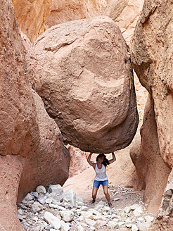Morocco, Boumalne Dades, Mature woman heavying rock - BSCF000066
