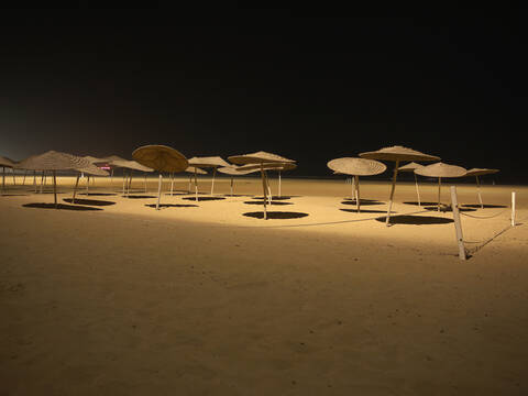 Marokko, Essaouira, Sonnenschirme am Strand bei Nacht, lizenzfreies Stockfoto