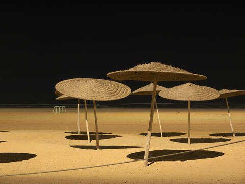 Marokko, Essaouira, Sonnenschirme am Strand bei Nacht, lizenzfreies Stockfoto