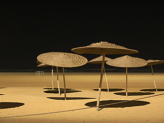 Marokko, Essaouira, Sonnenschirme am Strand bei Nacht - BSCF000084