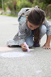 Deutschland, Bayern, Huglfing, Mädchen zeichnet mit Kreide auf der Straße - RIMF000024