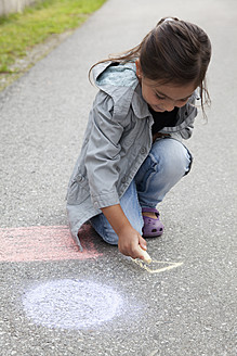 Deutschland, Bayern, Huglfing, Mädchen zeichnet mit Kreide auf der Straße - RIMF000017