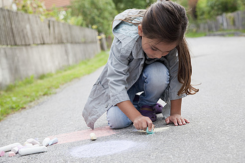 Deutschland, Bayern, Huglfing, Mädchen zeichnet mit Kreide auf der Straße - RIMF000016