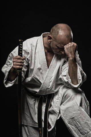 Deutschland, Bayern, Älterer Mann macht Karate vor schwarzem Hintergrund, lizenzfreies Stockfoto