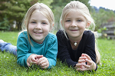 Germany, Bavaria, Huglfing, Girls lying on grass in garden, smiling, portrait - RIMF000031