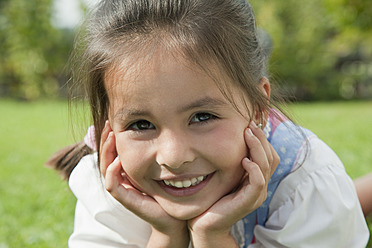 Germany, Bavaria, Huglfing, Girl in drindl lying on grass in garden, smiling, portrait - RIMF000039