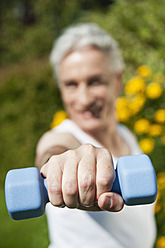 Germany, Bavaria, Mature man doing exercise with dumbbells - WESTF017623