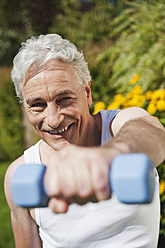 Germany, Bavaria, Mature man doing exercise with dumbbells - WESTF017624