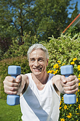 Germany, Bavaria, Mature man doing exercise with dumbbells - WESTF017625