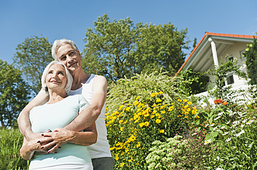 Deutschland, Bayern, Mann und Frau umarmen sich im Garten, lächelnd - WESTF017640