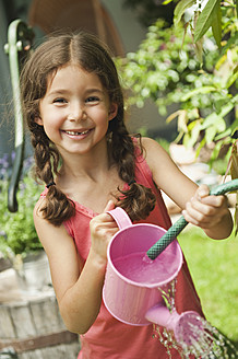 Germany, Bavaria, Girl gardening with watering can, smiling, portrait - WESTF017702