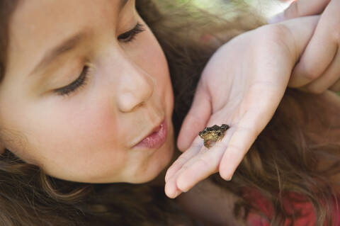 Germany, Bavaria, Girl looking at little frog on human hand stock photo