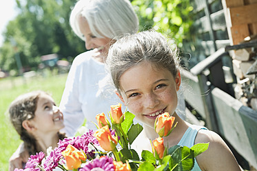 Deutschland, Bayern, Enkeltöchter und Großmutter im Garten, lächelnd - WESTF017736