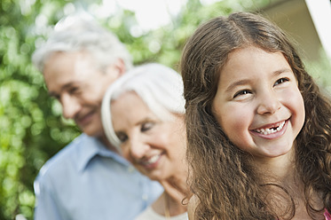 Germany, Bavaria, Girl smiling with grandparents in background - WESTF017739