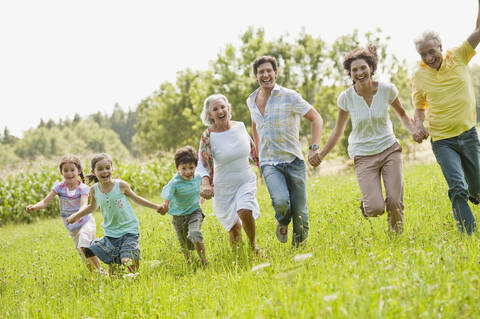 Deutschland, Bayern, Familie läuft zusammen im Gras beim Picknick, lizenzfreies Stockfoto