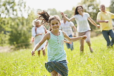 Germany, Bavaria, Family running together in grass at picnic - WESTF017776