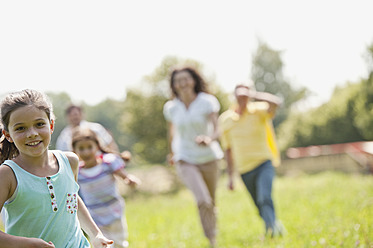 Deutschland, Bayern, Familie läuft zusammen im Gras beim Picknick - WESTF017777