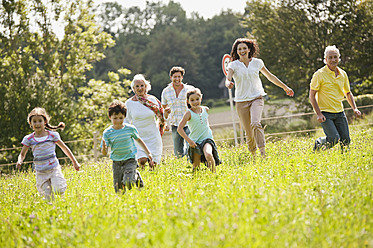 Deutschland, Bayern, Familie läuft zusammen im Gras beim Picknick - WESTF017778