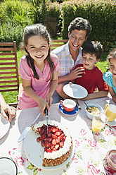 Germany, Bavaria, Family having coffee and cake in garden, smiling - WESTF017794