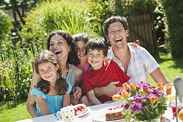 Deutschland, Bayern, Familie bei Kaffee und Kuchen im Garten, lächelnd - WESTF017797