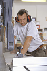 Germany, Upper Bavaria, Schaeftlarn, Carpenter working on sawing machine - TCF001865