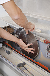 Germany, Upper Bavaria, Schaeftlarn, Carpenter fixing blade to electrical machine - TCF001867